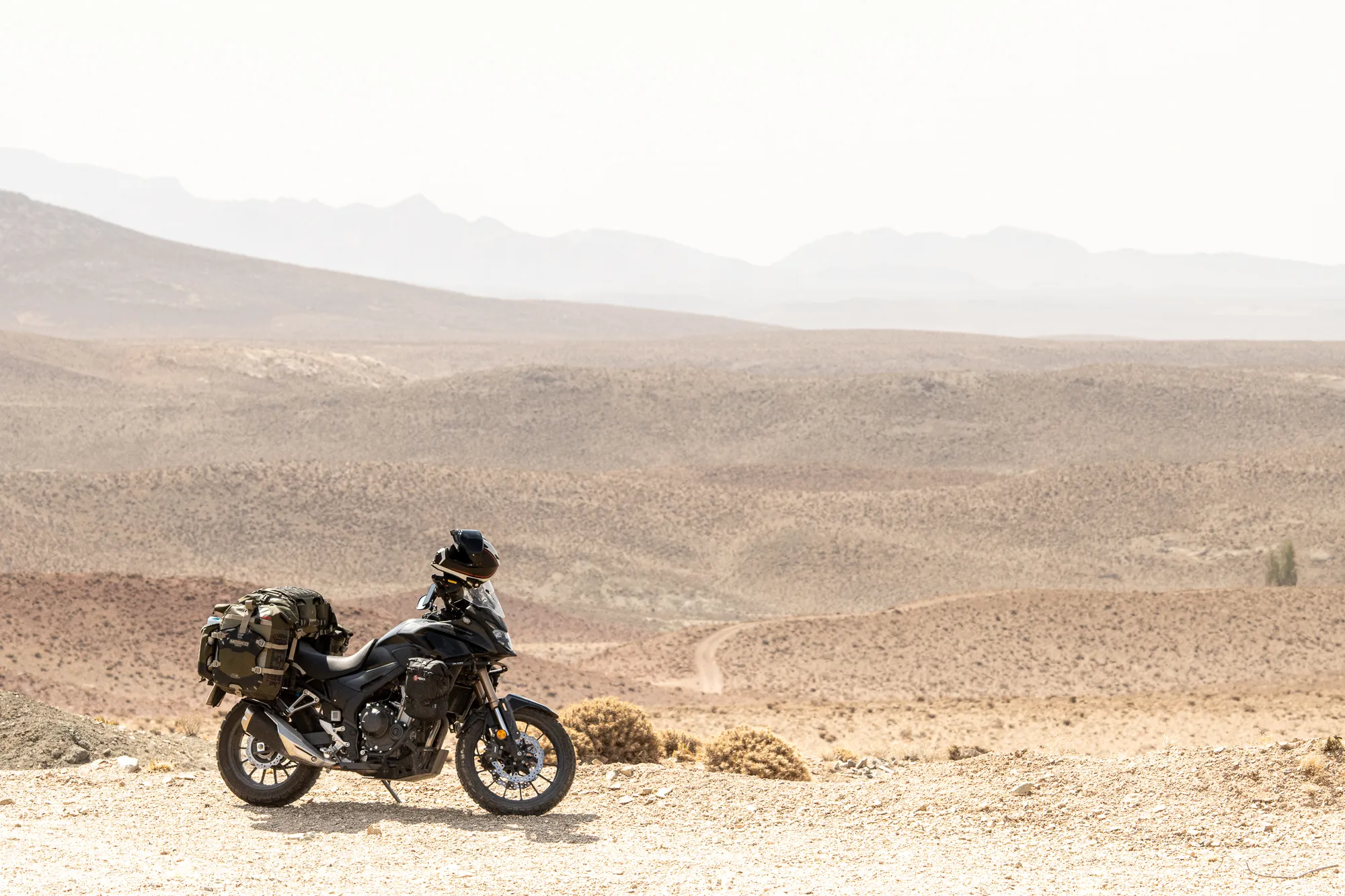 A loaded motorbike parked above a desert valley in Iran